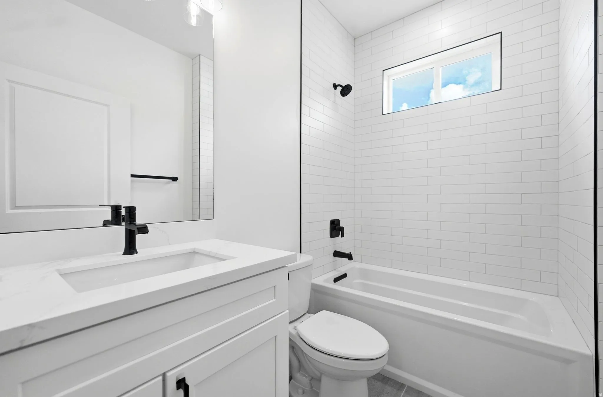 White subway tile shower surround with an integrated window, a white vanity with a rectangular undermount sink, and matte black fixtures