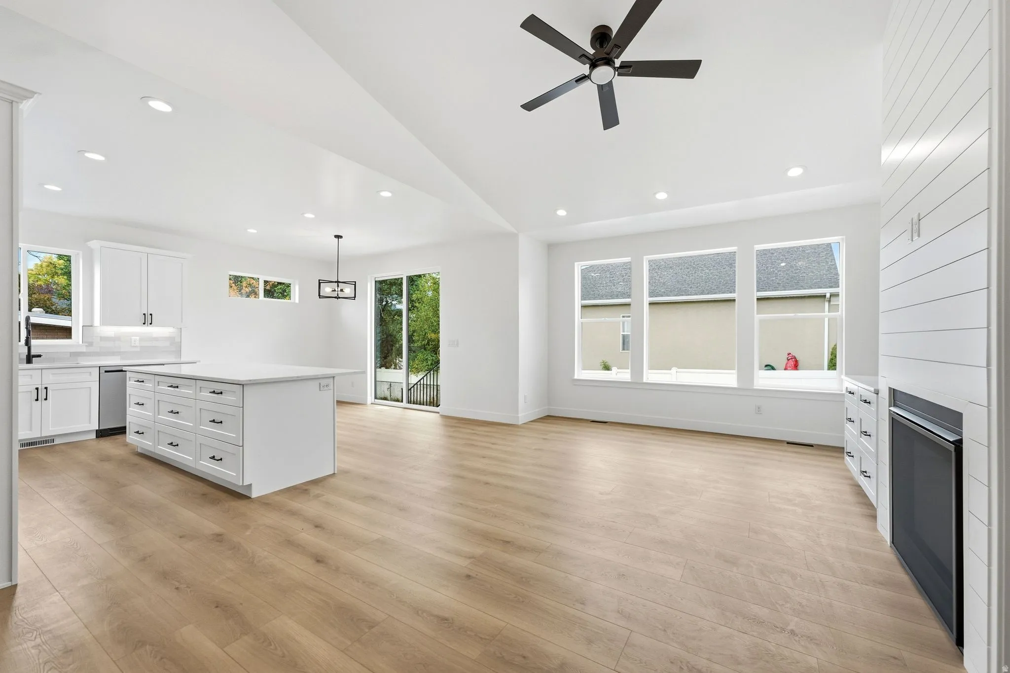 Open-concept living space with wood- flooring, recessed lighting, and a vaulted ceiling