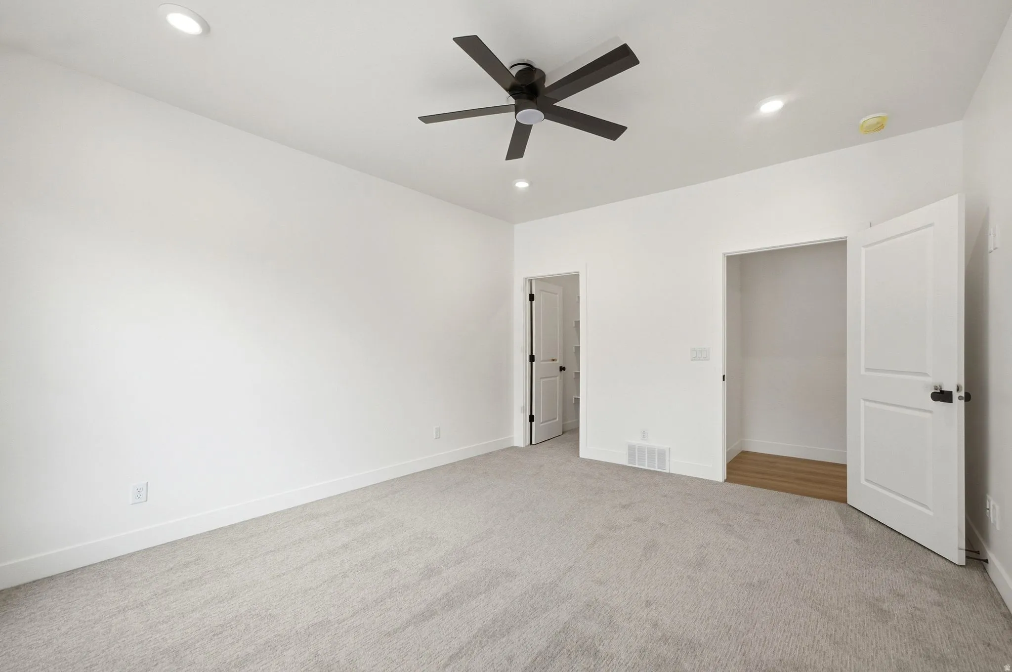 Bright room featuring recessed lighting, a ceiling fan, light-toned carpeting, and a closet with wood-finish flooring
