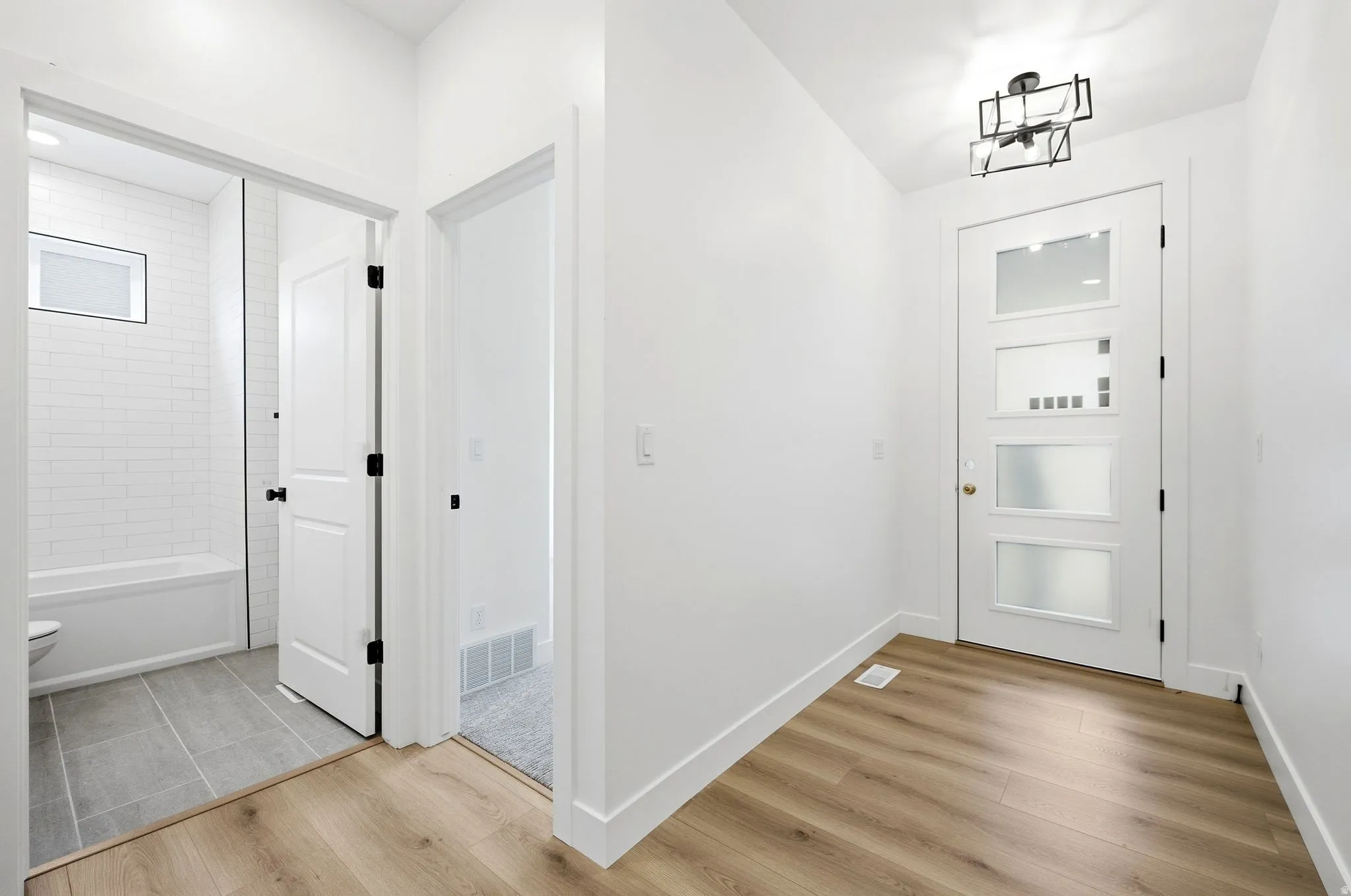 Entryway with wood-finish flooring, a modern geometric flush mount light, and a white door with frosted glass panels