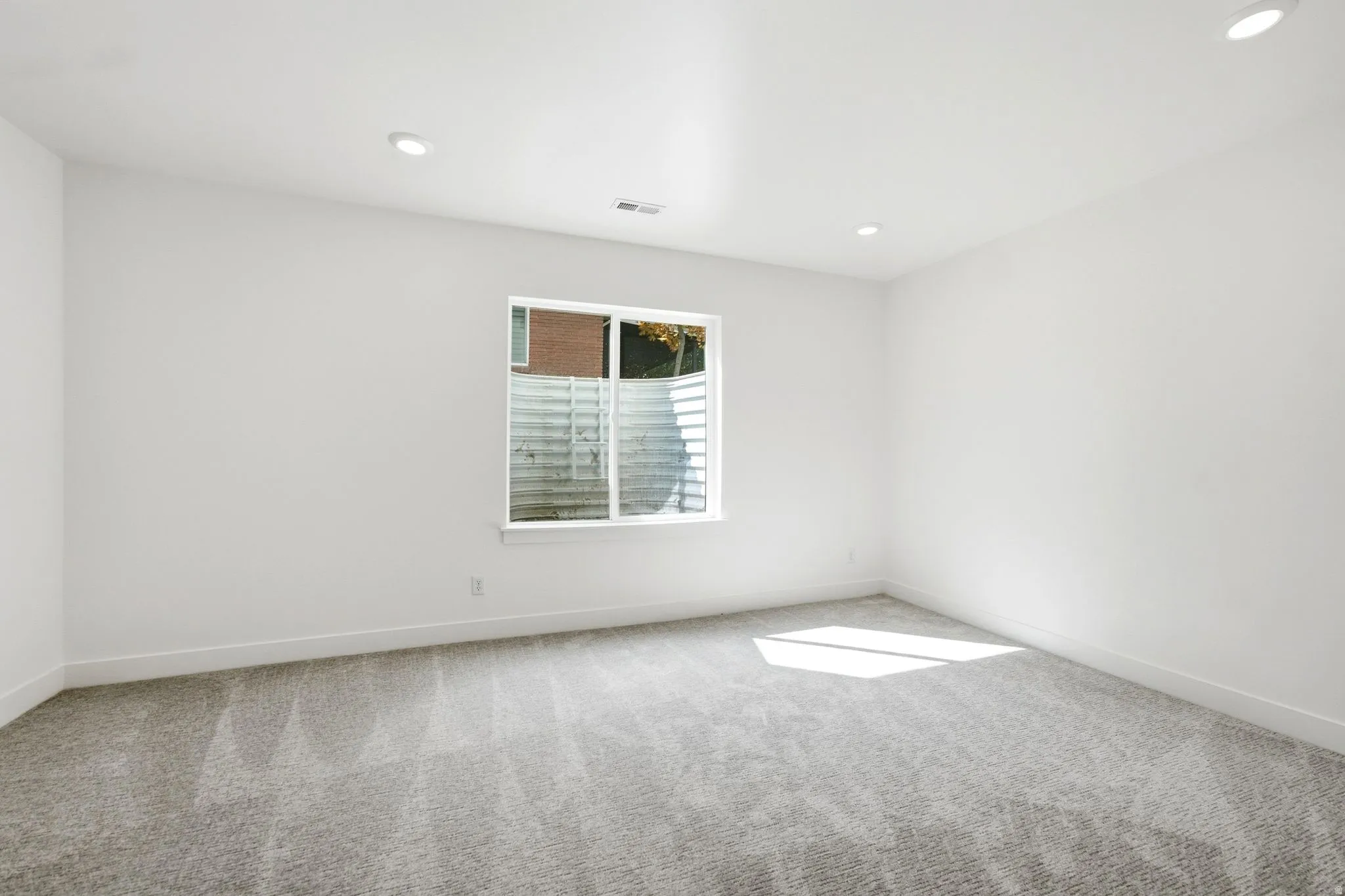 Recessed lighting, light gray carpeting, white walls, and a single window