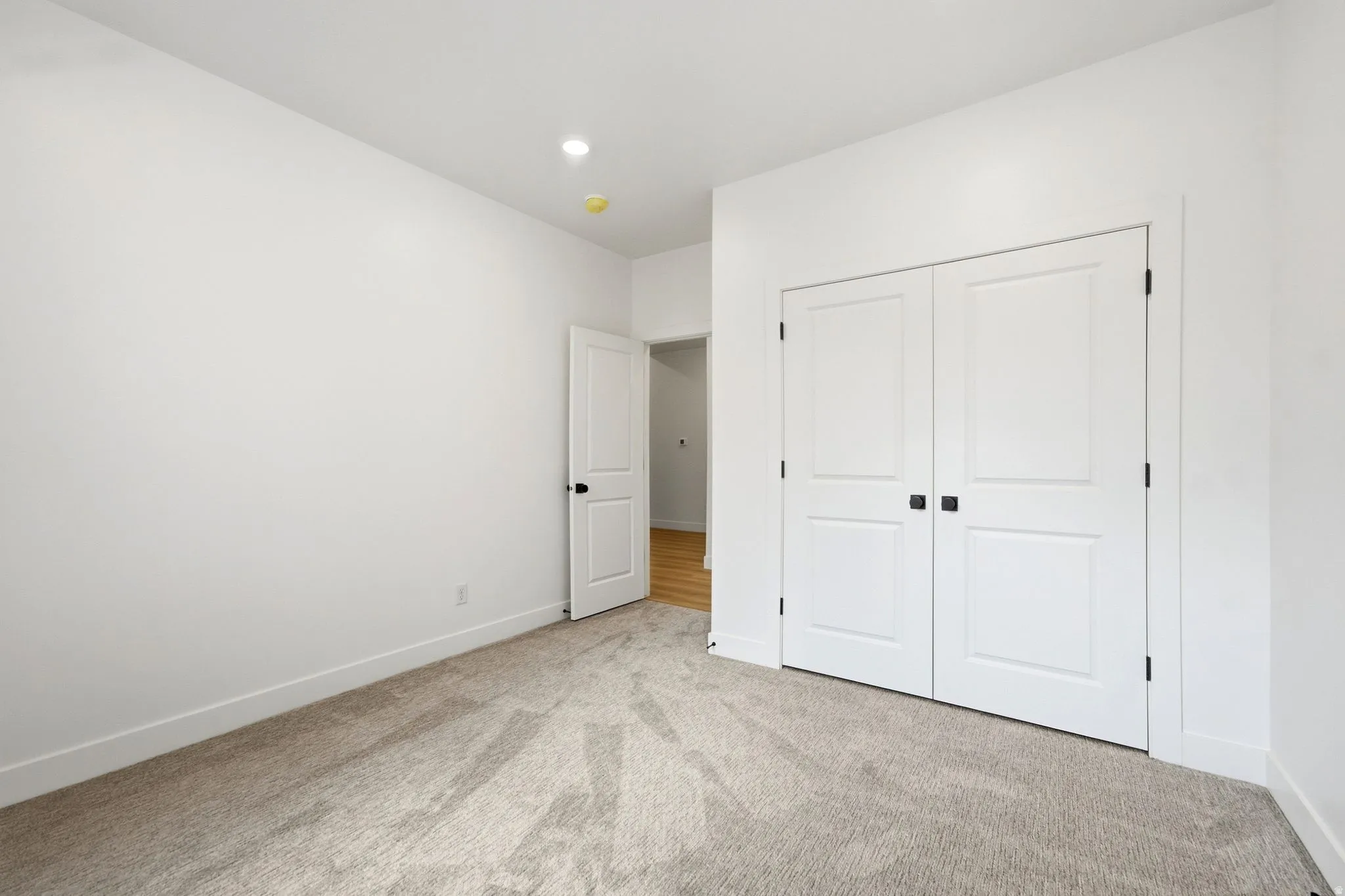Plush carpeting, recessed lighting, and a bi-fold closet with black hardware