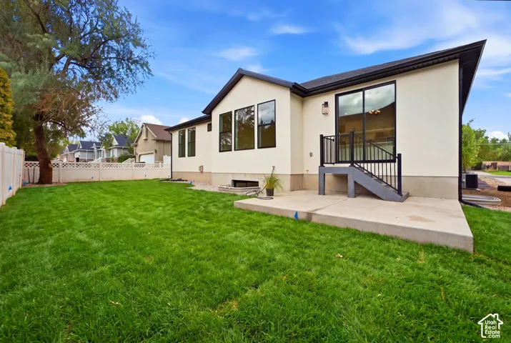 Manicured lawn, stucco exterior, large sliding glass door, black-framed windows, and concrete patio