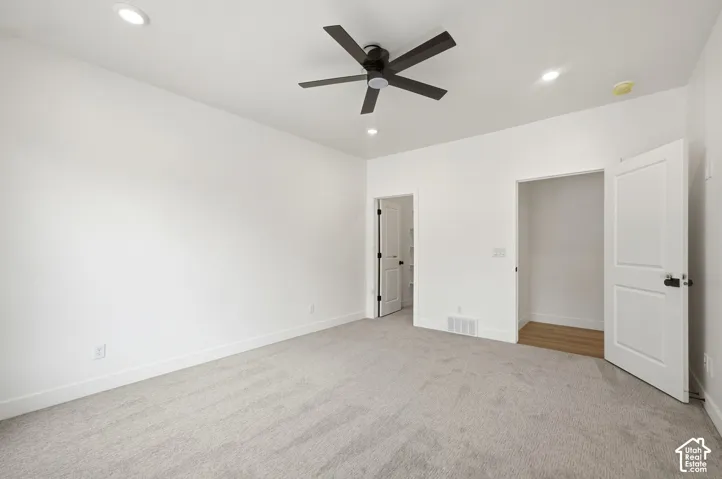 Bright room featuring recessed lighting, a ceiling fan, light-toned carpeting, and a closet with wood-finish flooring