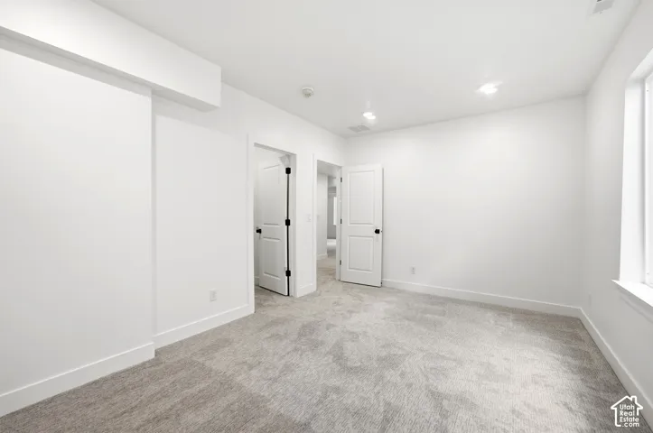 Neutral toned carpeting, white walls, recessed lighting, and white trim