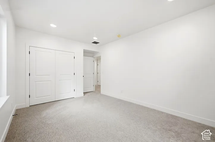 Recessed lighting, neutral wall paint, carpeted flooring, and a window