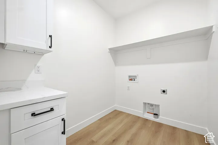 White shaker-style cabinetry with matte black hardware, stone-look countertop, wood-finish flooring, and built-in wall shelving