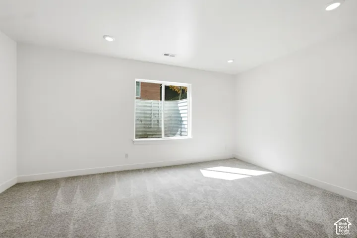 Recessed lighting, light gray carpeting, white walls, and a single window