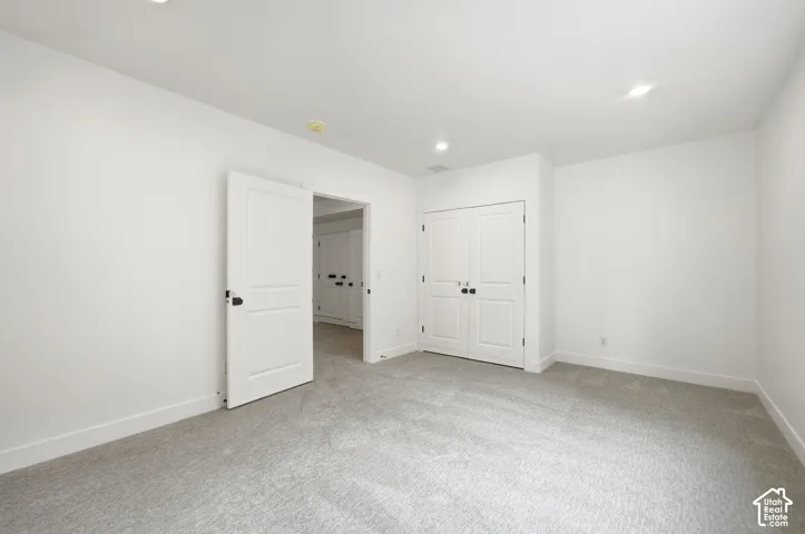 Plush gray carpeting, white walls, recessed ceiling lighting, and white panel doors with black hardware