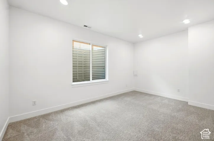 Recessed lighting, light-toned carpeting, white walls, and a sliding window
