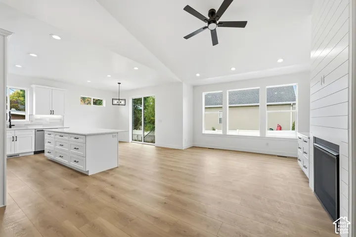 Open-concept living space with wood- flooring, recessed lighting, and a vaulted ceiling