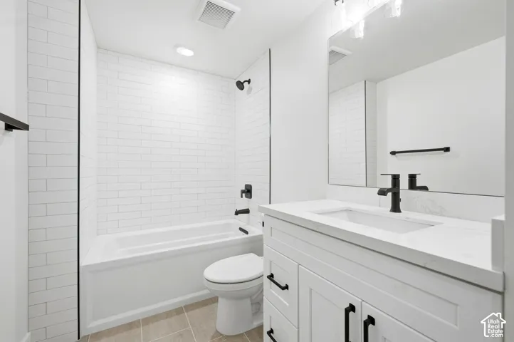 White subway tile shower surround, matte black fixtures, integrated sink, white vanity with paneled doors, and light-toned tile flooring