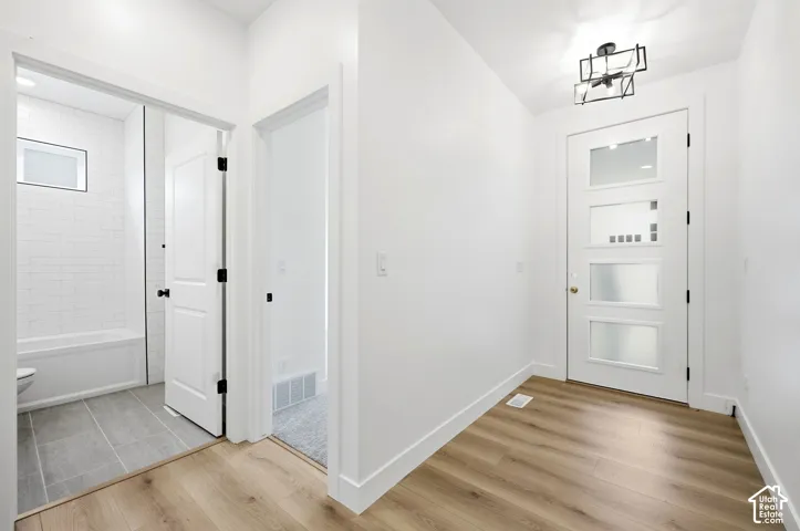 Entryway with wood-finish flooring, a modern geometric flush mount light, and a white door with frosted glass panels