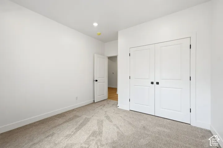 Plush carpeting, recessed lighting, and a bi-fold closet with black hardware