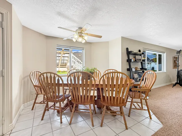 Tiled flooring, ceiling fan with integrated lighting, multiple windows, and baseboard molding