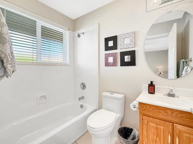 Bathroom featuring a full tub with shower, wood-finish vanity with countertop, and an oval mirror