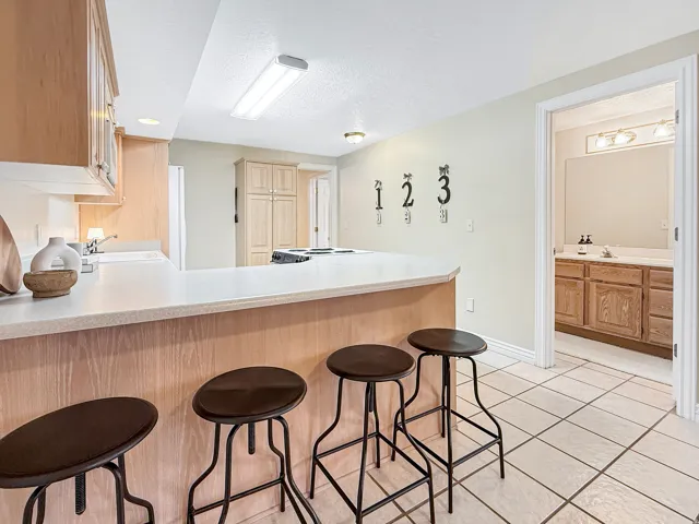 Kitchen with a breakfast bar, light wood-finish cabinetry, and recessed lighting