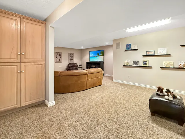 Built-in cabinetry with light wood finish, recessed lighting, wall-mounted shelving, and carpeted flooring