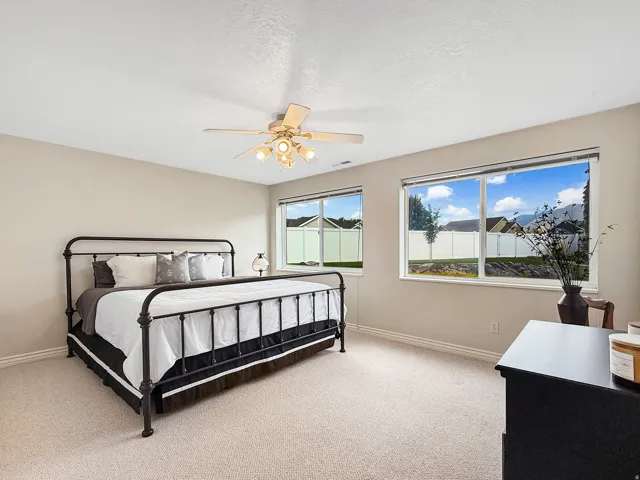 Bright interior with two large windows, neutral wall paint, and light-toned carpet flooring