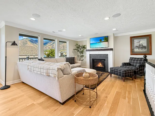 Living area featuring light wood-finish flooring, a contemporary fireplace with a dark tile surround and white mantel, and a multi-pane window assembly