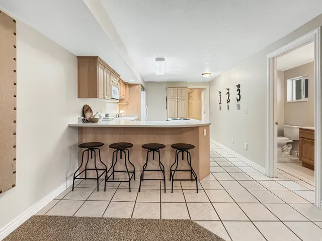 Kitchenette with wood-finish cabinetry, white countertops, and a breakfast bar