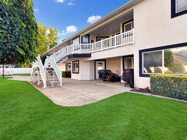Exterior concrete patio with direct access to interior spaces, featuring a second-story balcony with white railing