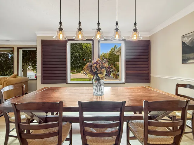Dining area featuring a wood-finish table, plantation shutters, and a five-light pendant fixture