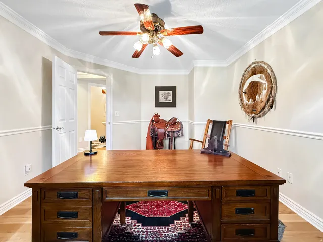 Hardwood flooring, crown molding, chair rail molding, ceiling fan with integrated lighting, and a paneled door
