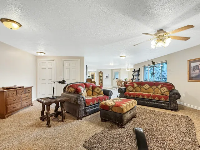 Spacious recreation room featuring neutral carpet flooring, recessed and ceiling fan lighting throughout, dual closets with six-panel doors, and wooden cabinetry