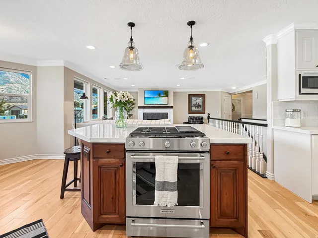 Kitchen island with stainless steel range, white countertop, and wood-finish cabinetry