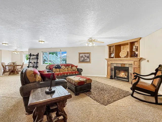 Living space featuring a built-in fireplace with stone surround, integrated shelving, and carpet flooring