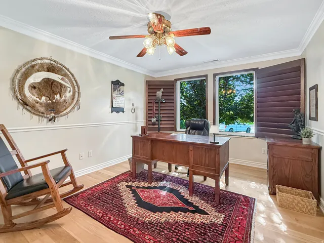 Crown molding accents, wood-finish flooring, and a ceiling fan with integrated lighting