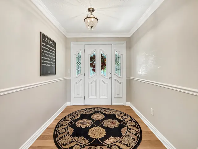 Double entry doors with decorative glass panels, crown molding, chair rail molding, and wood-finish flooring