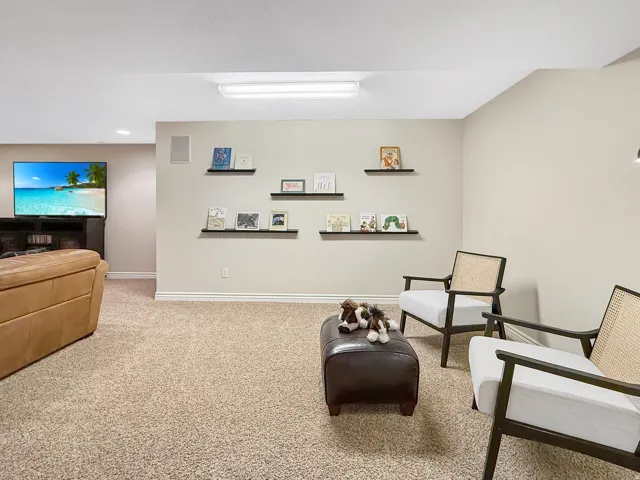 Carpeted room featuring light-toned walls, recessed ceiling lights, and built-in wall shelving