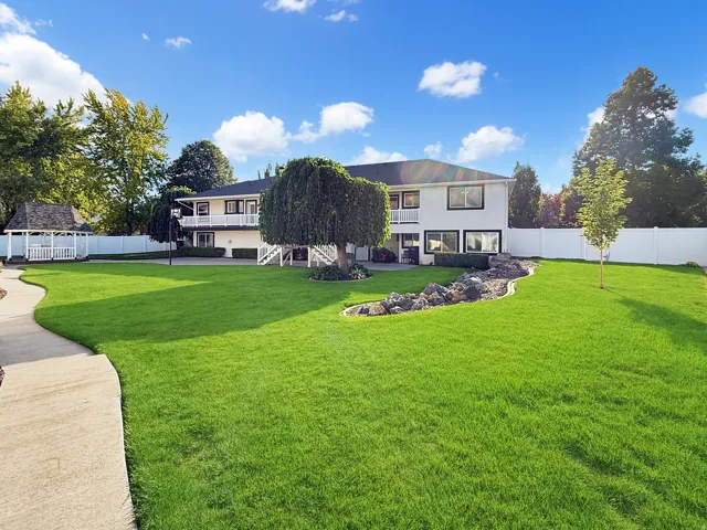 Expansive manicured lawn with mature landscaping and curved concrete walkway