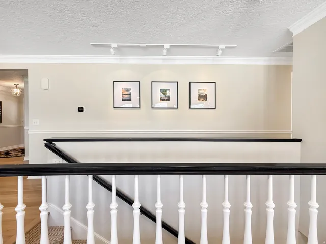 Hardwood flooring, painted balusters, and a black handrail