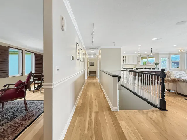 Wood-finish flooring throughout, white crown molding, white chair rail molding, white balusters, and a dark wood banister