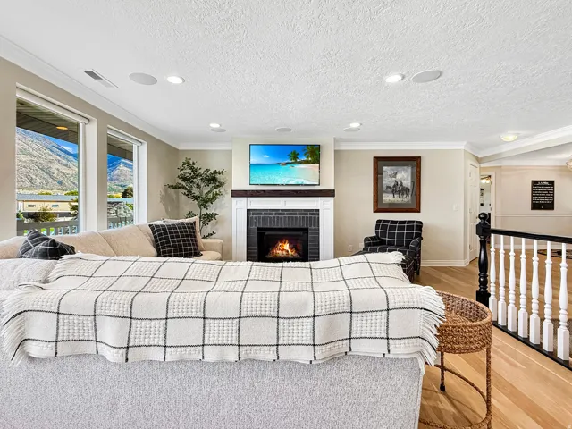 Living area featuring a fireplace with a dark tile surround and wood mantel, large windows, recessed lighting, and hardwood flooring