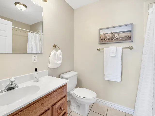 Vanity with a wood-finish cabinet and white countertop, integrated sink, and clear acrylic faucet handles