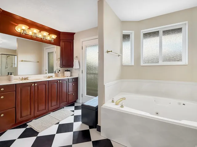 Dual vanity with wood-finish cabinetry, white countertop, and gold-tone fixtures