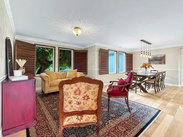 Hardwood flooring throughout, crown molding, plantation shutters, and a dining area with a linear pendant light fixture
