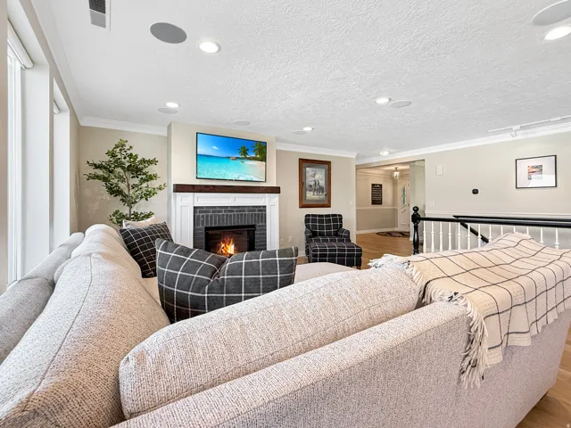 Recessed lighting, crown molding, and a built-in fireplace with a dark tile surround and wood mantel