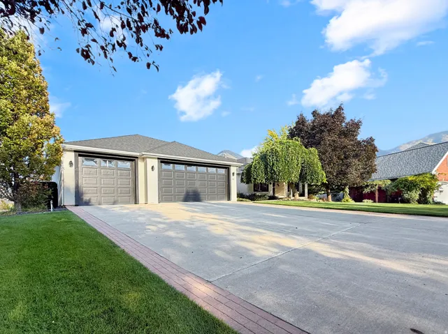 Concrete driveway with brick border, attached two-car garage, and established landscaping