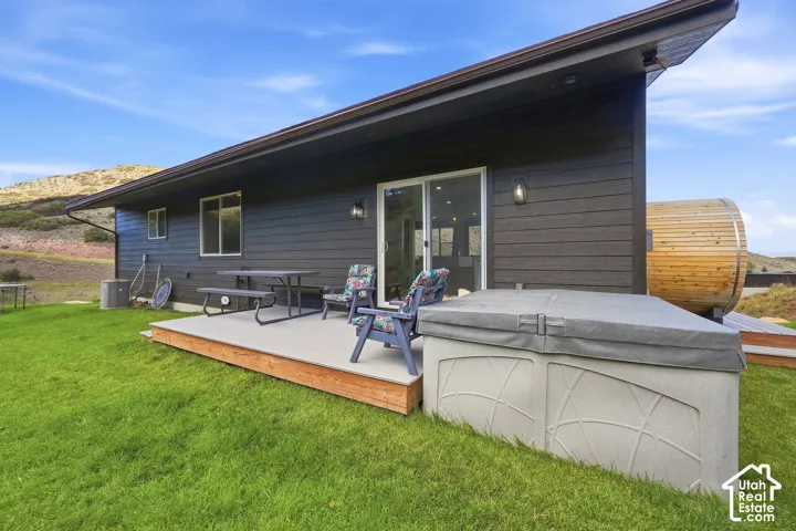 Rear exterior featuring a wood-look deck, sliding glass door, and a spa