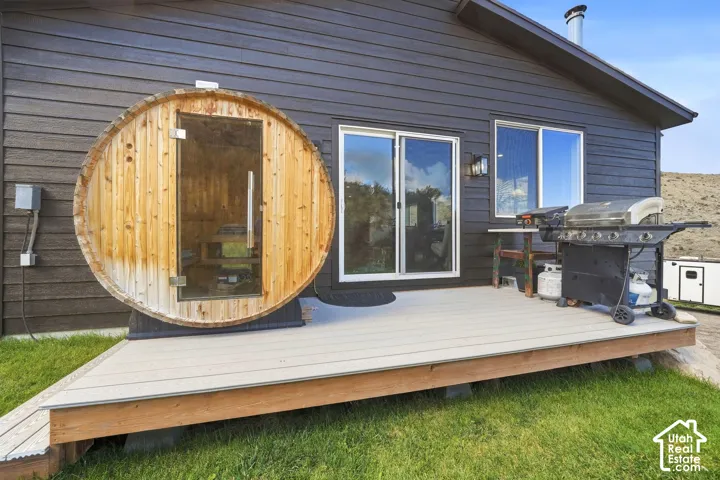 Back exterior with a barrel sauna, composite decking, black horizontal siding, and white-framed sliding glass doors