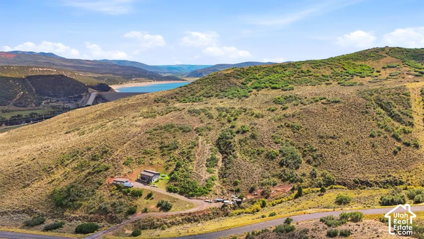Expansive natural landscape featuring rolling hills and distant water body