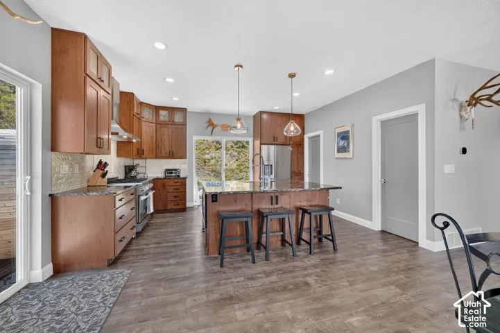 Wood-finish flooring, stainless steel appliances, and a central island with bar seating