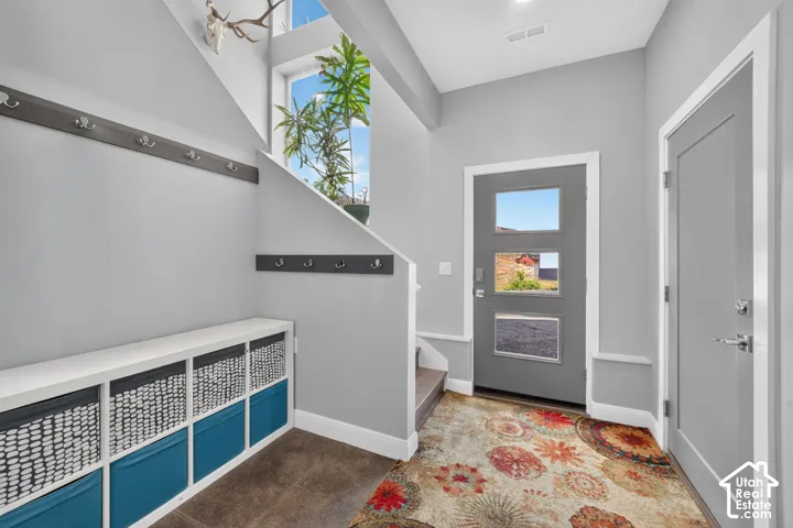 Entryway with a contemporary gray door featuring three square lites, high ceilings, and a built-in storage bench