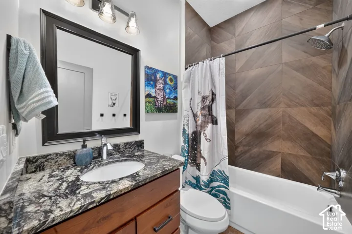 Modern bathroom featuring a wood-finish vanity with a stone countertop, an undermount sink, and a framed mirror