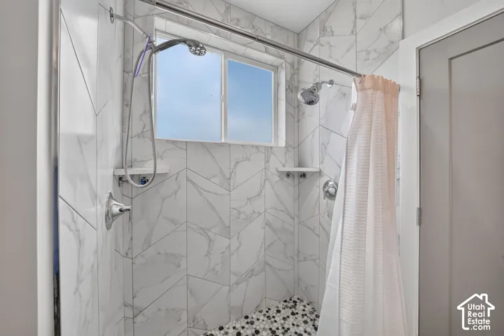 Tiled shower with a window, dual shower heads, and pebble-finish flooring